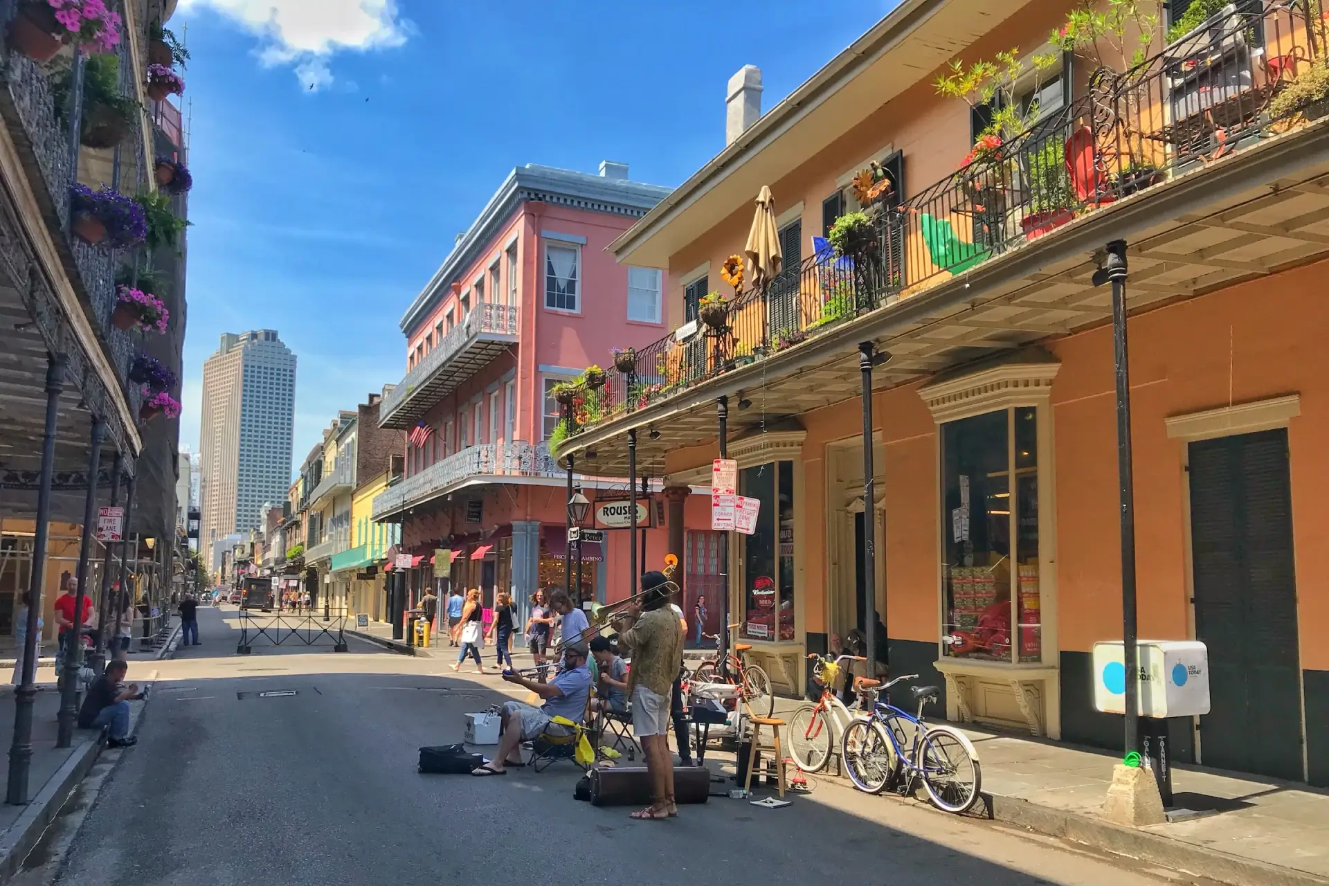 A colorful street in New Orleans with a band playing music on the street and people walking around the colorful buildings.