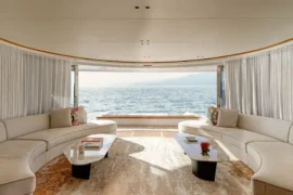 Spacious main salon aboard Cada Dia featuring curved lounge seating, soft neutral tones, and panoramic ocean views for relaxed luxury at sea.