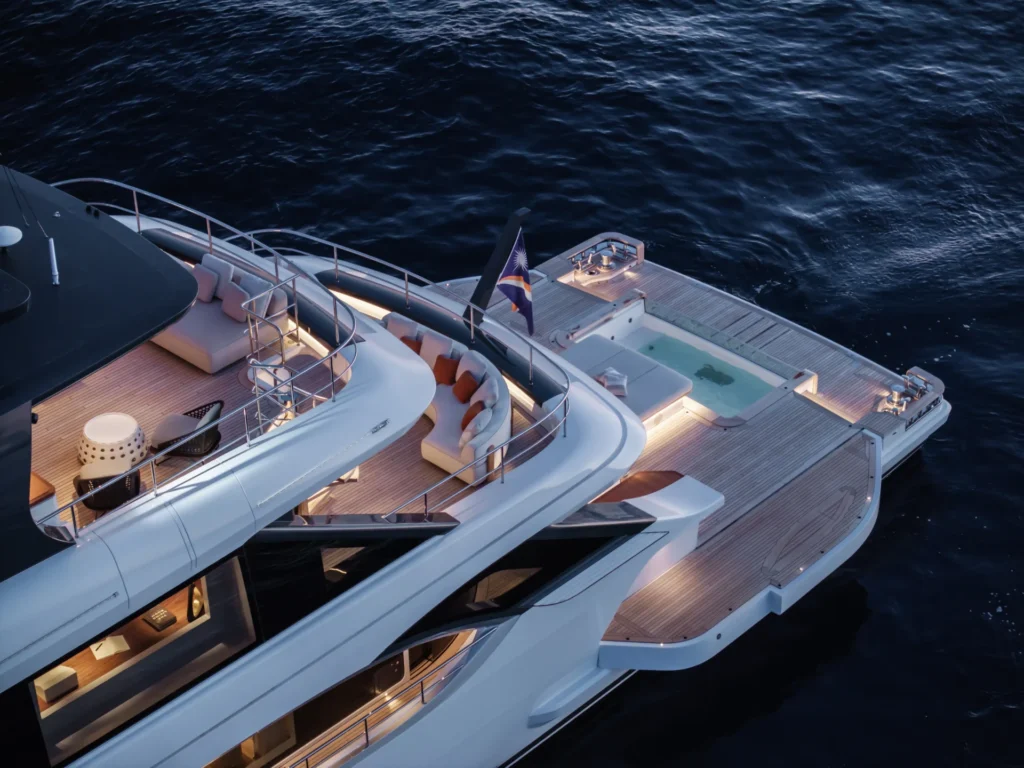 Elevated view of Cada Dia’s aft beach club featuring a large teak swim platform, built-in spa pool, and stylish lounge seating just above the sea.