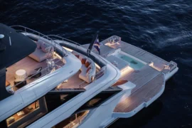 Elevated view of Cada Dia’s aft beach club featuring a large teak swim platform, built-in spa pool, and stylish lounge seating just above the sea.