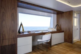 Refined interior work and vanity space aboard Cada Dia with rich wood finishes, ocean-view window, and a calm, contemporary luxury design.