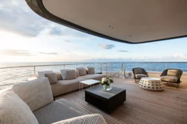 Open-air aft deck lounge on Cada Dia with plush seating, teak decking, and sweeping ocean views designed for cocktails, conversation, and sunset cruising.