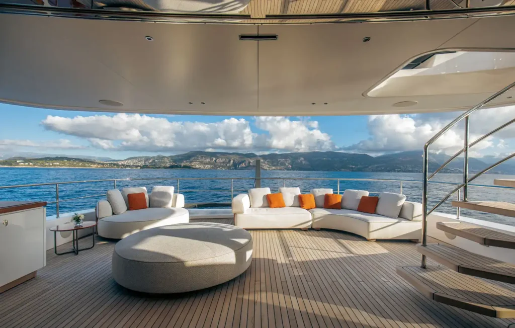 Private stern lounge aboard Cada Dia with curved sofas, teak decks, and scenic coastal views, creating a calm and elegant space to unwind on the water.