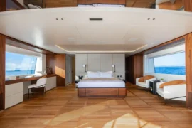 Full-beam master suite on Cada Dia featuring warm wood finishes, expansive windows, and a serene, spacious layout designed for exceptional comfort at sea.