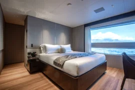 Elegant guest stateroom aboard Cada Dia with refined finishes, ocean-view windows, and a quiet, contemporary design for restful overnight accommodations.