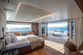 Luxurious owner’s suite on Cada Dia with a private aft terrace, oversized windows, and rich wood detailing for an elevated onboard retreat.