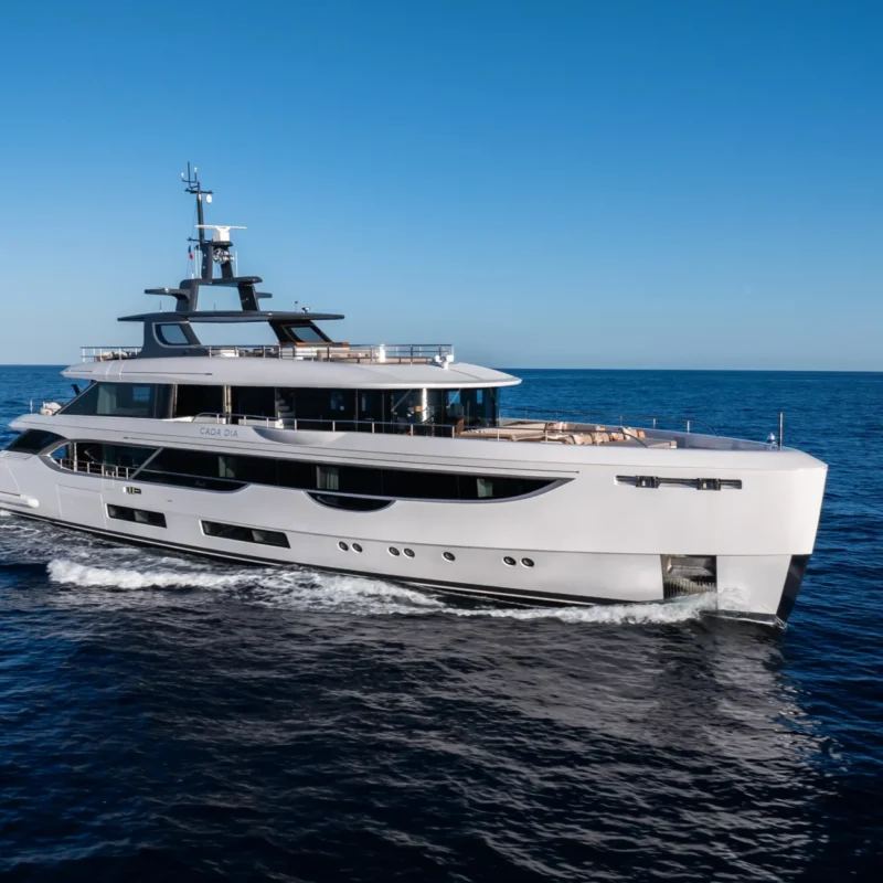 Side profile of Cada Dia underway, highlighting her modern exterior lines, generous deck spaces, and elegant long-range cruising presence at sea.